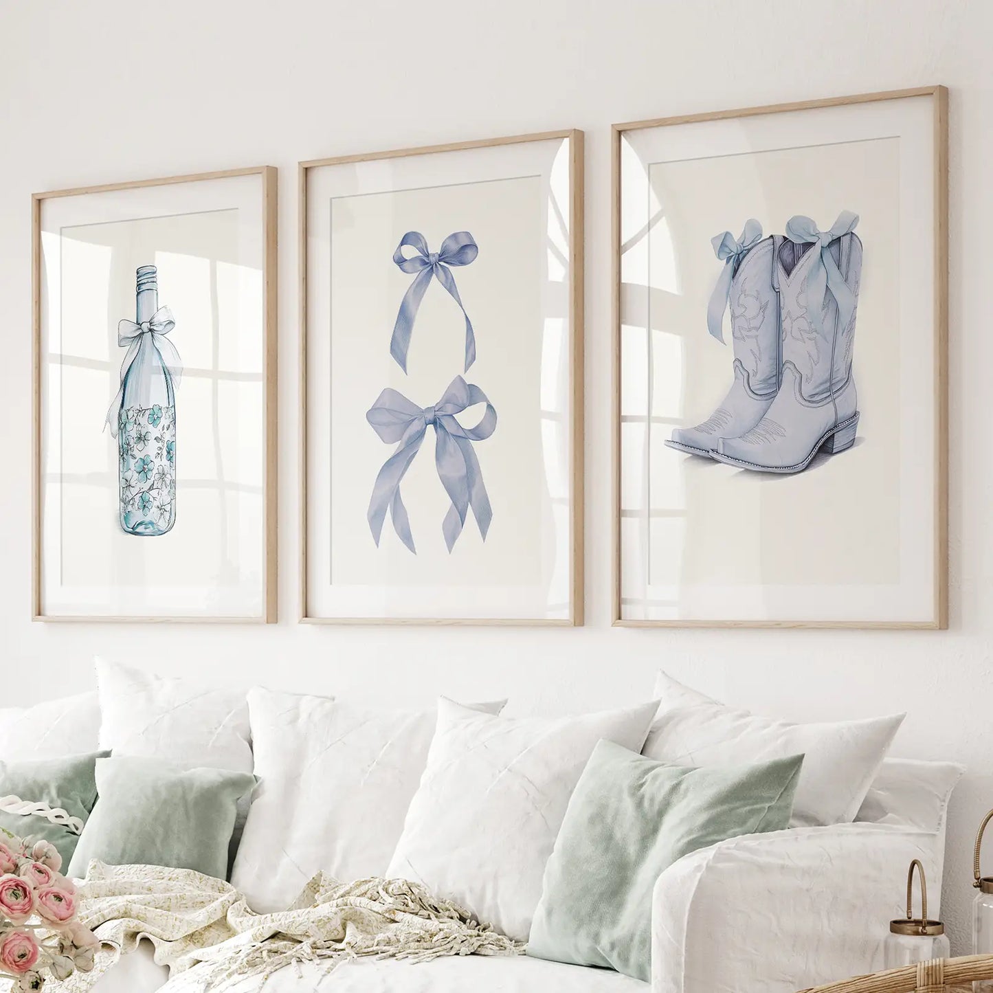 Set of 3 wall art prints with blue floral wine bottle, bows and cowboy boots. Thinwood frames with mat over the couch.