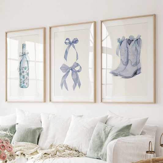 Set of 3 wall art prints with blue floral wine bottle, bows and cowboy boots. Thinwood frames with mat over the couch.
