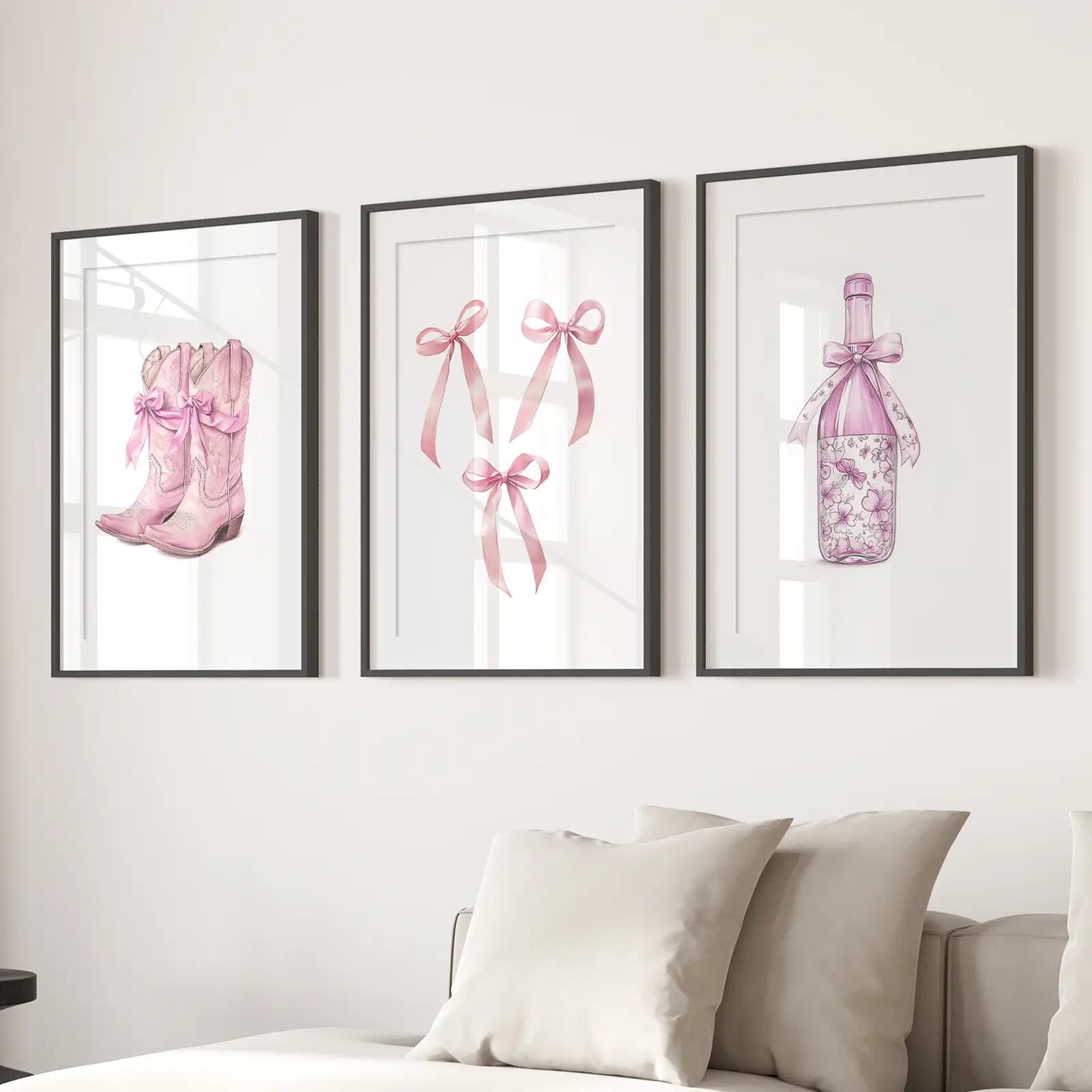 Pink aesthetic western wall art set of 3 – cowboy boots, bows, and bottle prints. Black frames with mat above the sofa.
