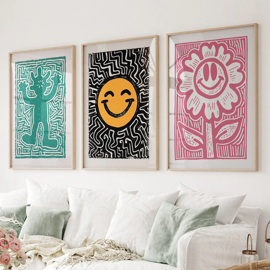 Pop art wall art set of 3 with teal figure, smiley face, and pink flower print. Thinwood frames over the couch.