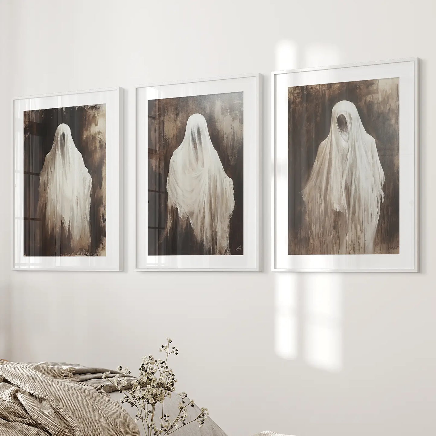 Seasonal fall holiday ghosts wall art prints decor set. White frames with mat above the bed.