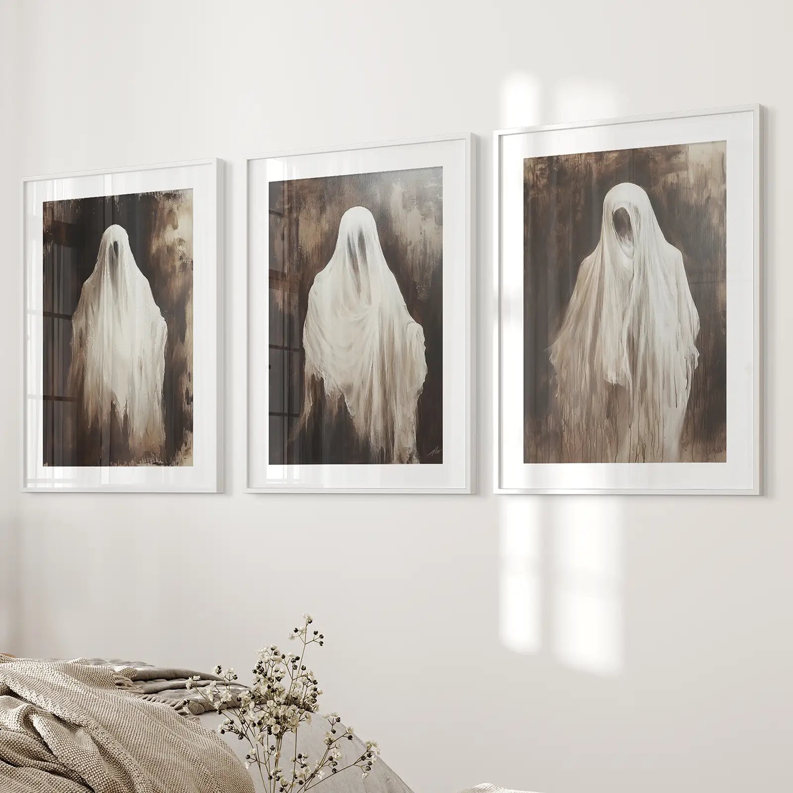 Seasonal fall holiday ghosts wall art prints decor set. White frames with mat above the bed.