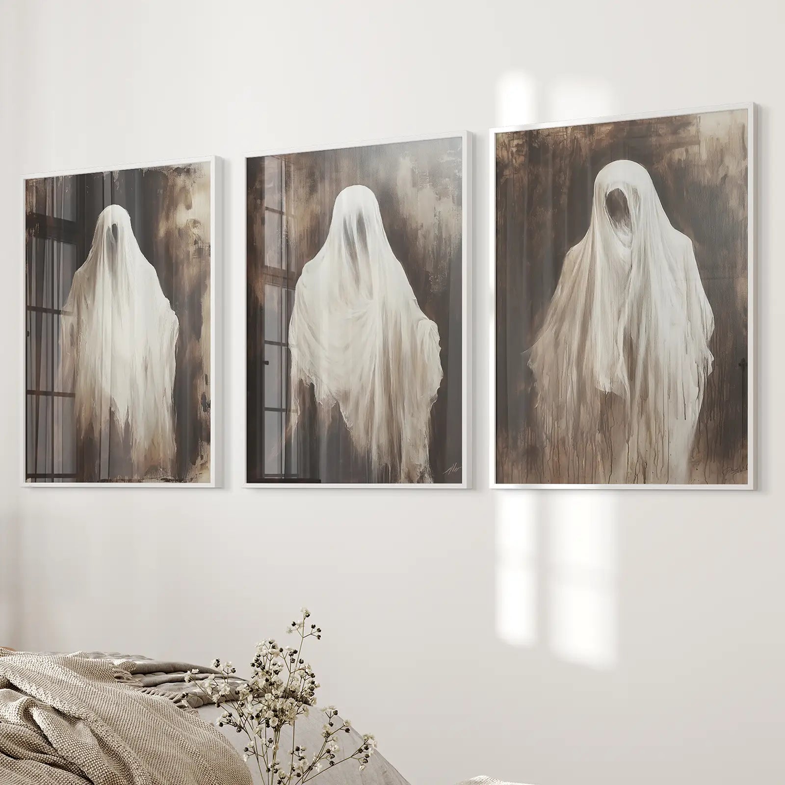 White ghost silhouette wall art set of 3 spooky haunted prints. White frames over the bed.