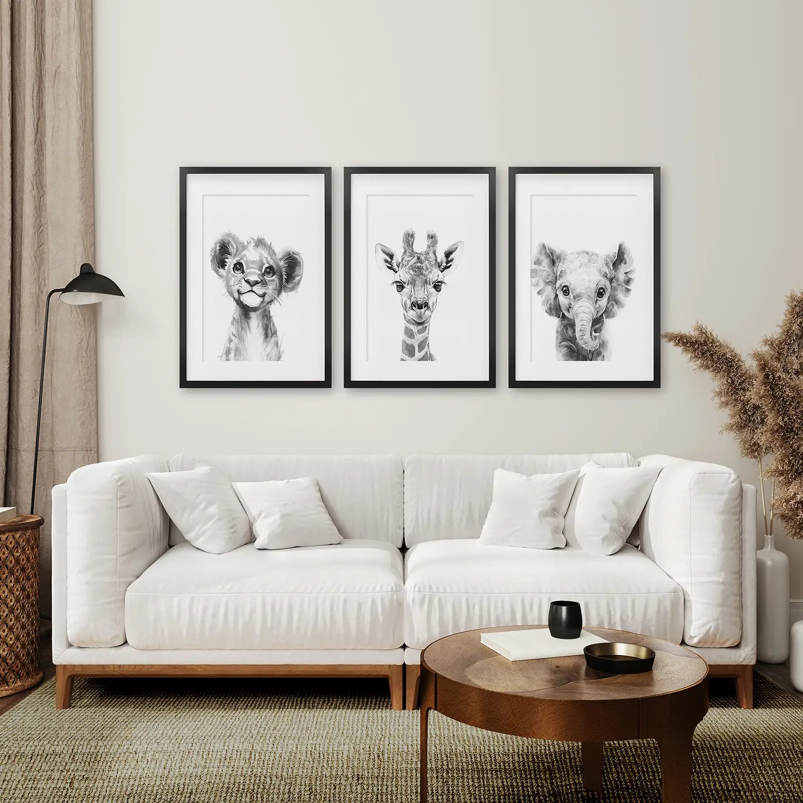 Playful nursery art trio with lion cub, giraffe calf, and baby elephant. Black frames with mat above the sofa.