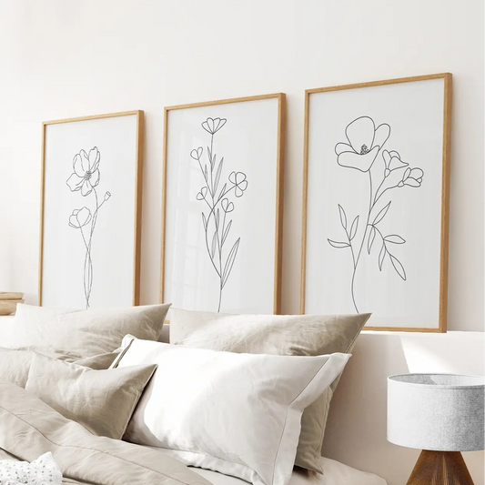Modern floral sketches black and white botanical wall decor triptych. Thinwood frames over the bed.