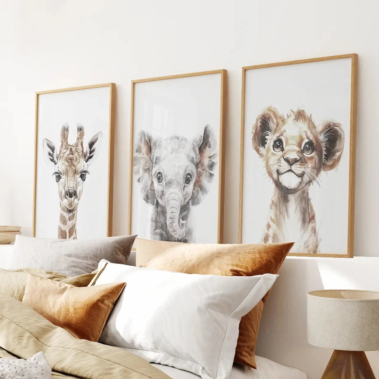Neutral nursery wall art with watercolor baby giraffe, elephant, and lion illustrations. Thinwood frames over the bed.