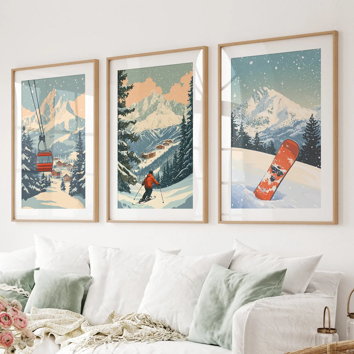 3 piece wall art of snowy mountain scenes with skiers and a snowboard, displayed on a wall above a sofa. Wood frames with mat