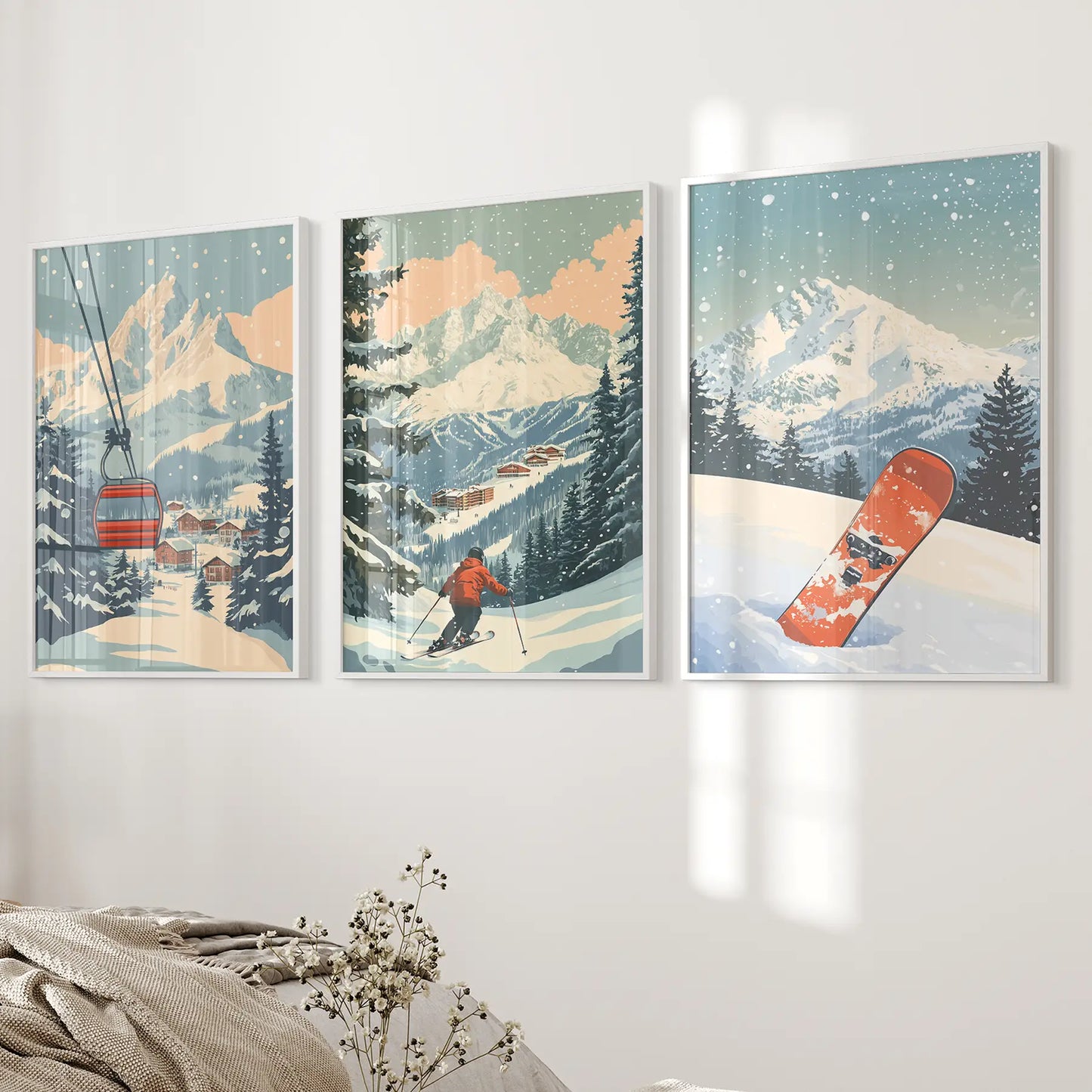 Set of 3 framed artworks depicting ski scenes with mountains, a skier, ski lift, and a snowboard. White frames