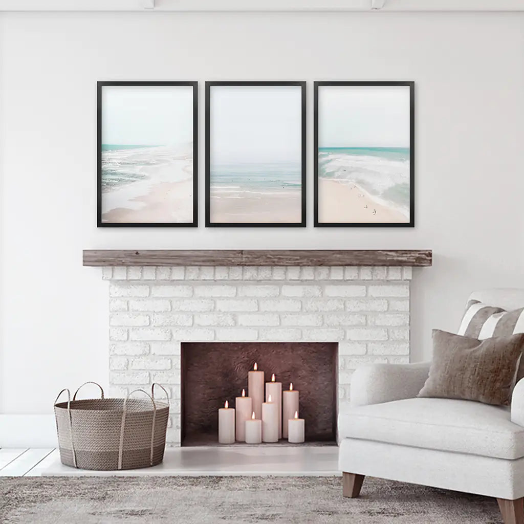 Set of 3 coastal prints. Blue sea and sandy beach with vacationers. Black frames over the fireplace.