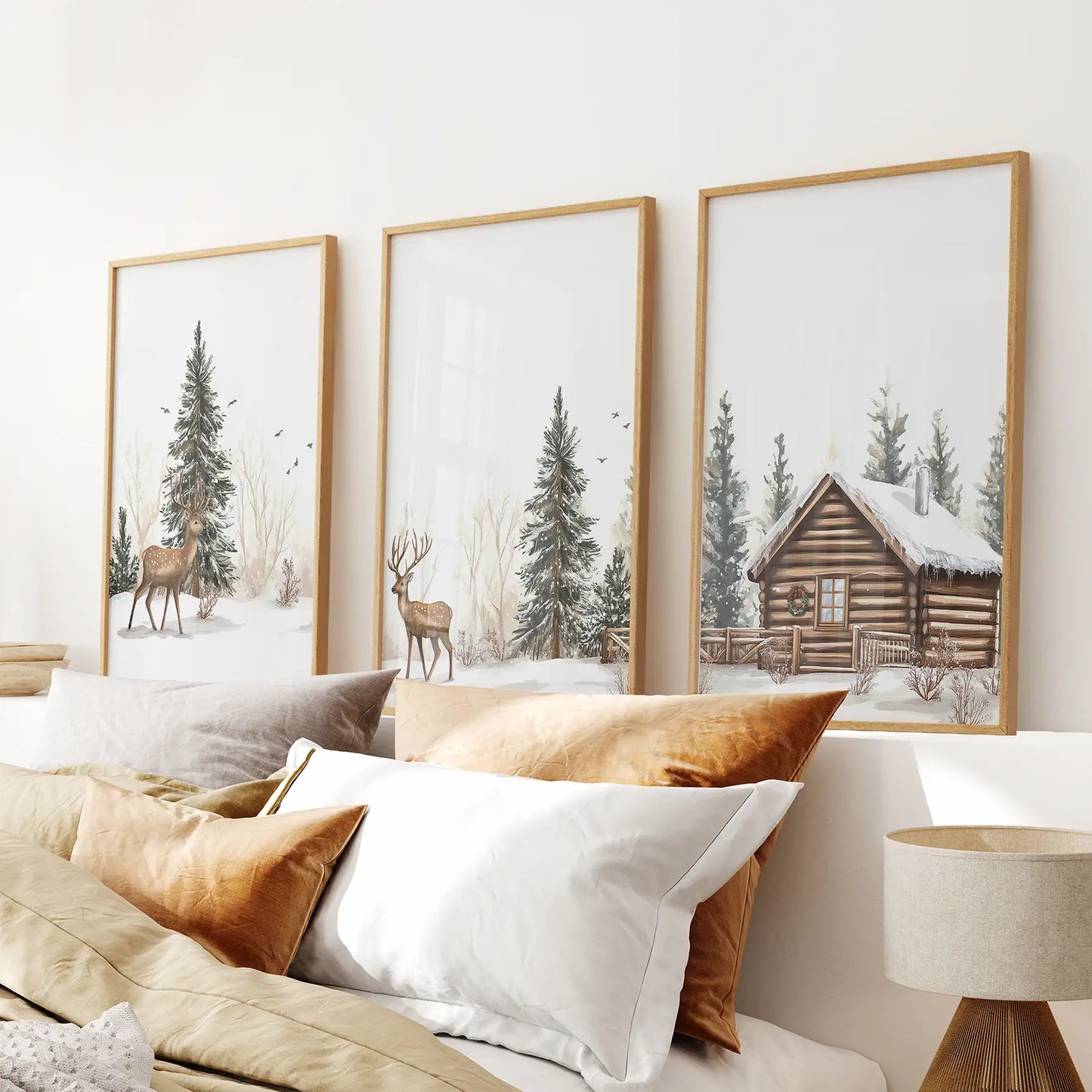 Cozy wall art set of 3 with forest deer, snowy evergreens, and a wooden cabin. Thinwood frames above the bed.