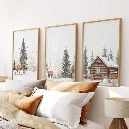 Cozy wall art set of 3 with forest deer, snowy evergreens, and a wooden cabin. Thinwood frames above the bed.
