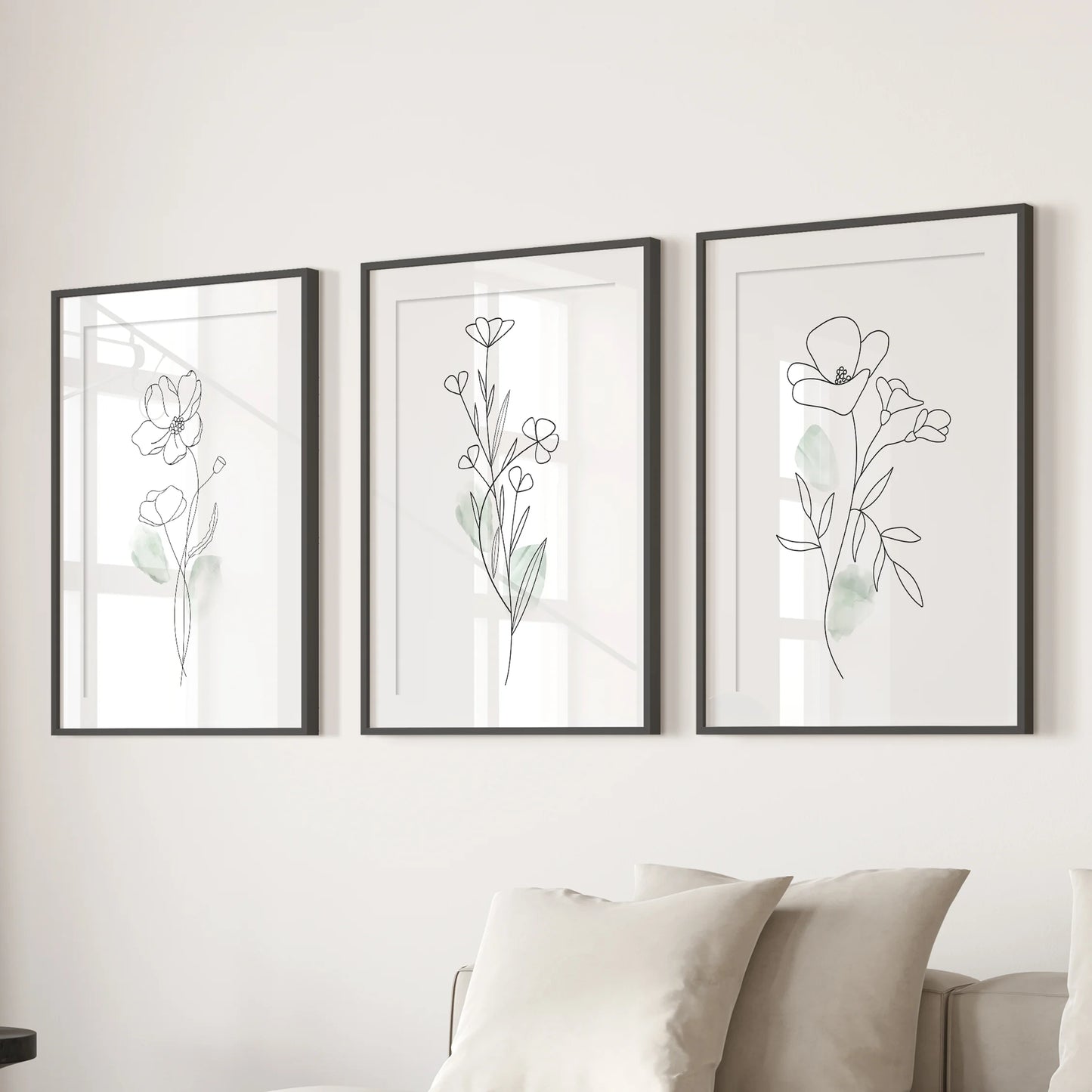 A three-piece set of abstract botanical art hangs above the living room sectional, wide-matted black frames adding gallery-style polish and order.