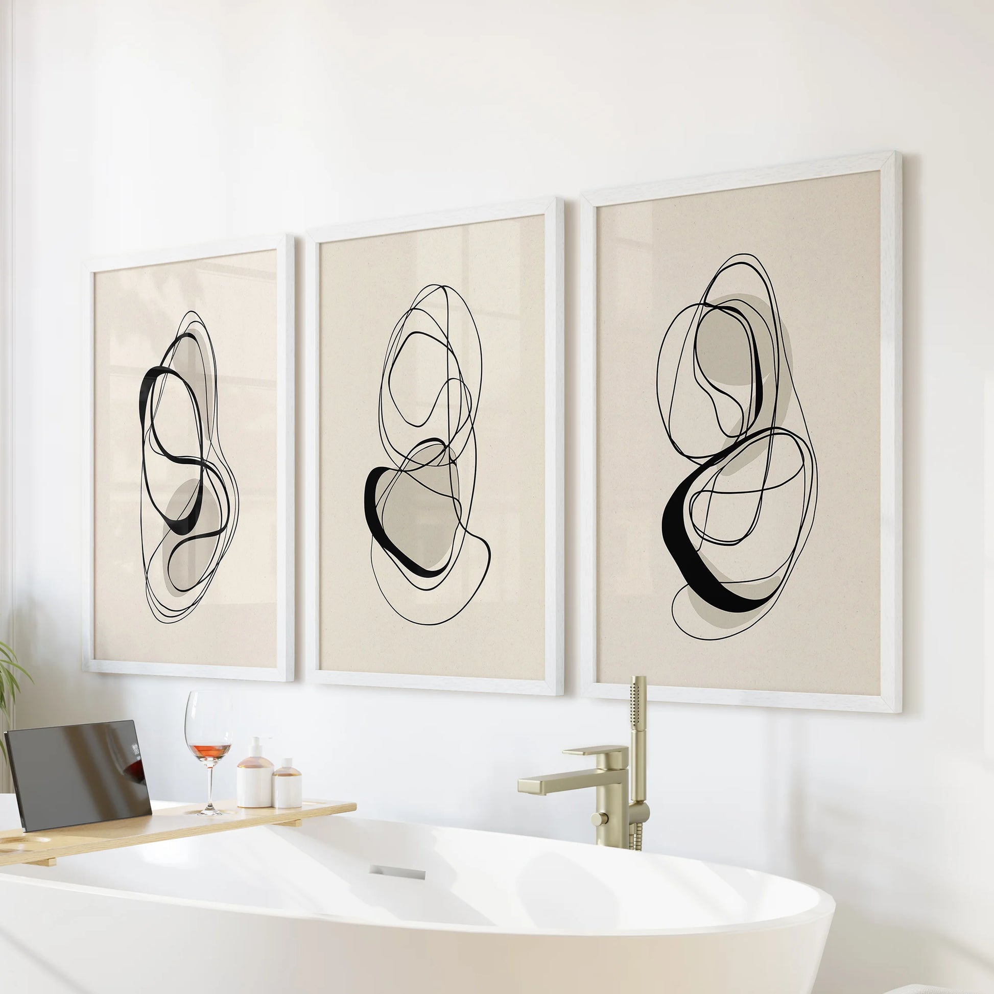Set of three abstract line-art prints in crisp white frames, poised above the bath to lend a soft geometric touch to a spa-like bathroom.