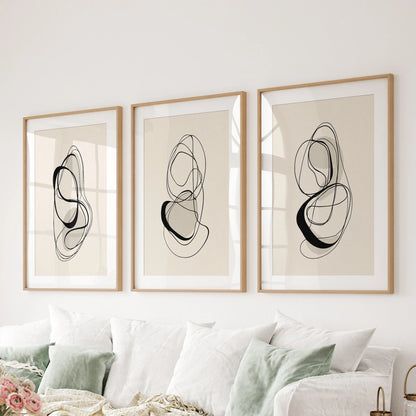Three-piece abstract line-art wall hanging in matted wooden frames, styled behind the couch to give the sitting room calm structure.