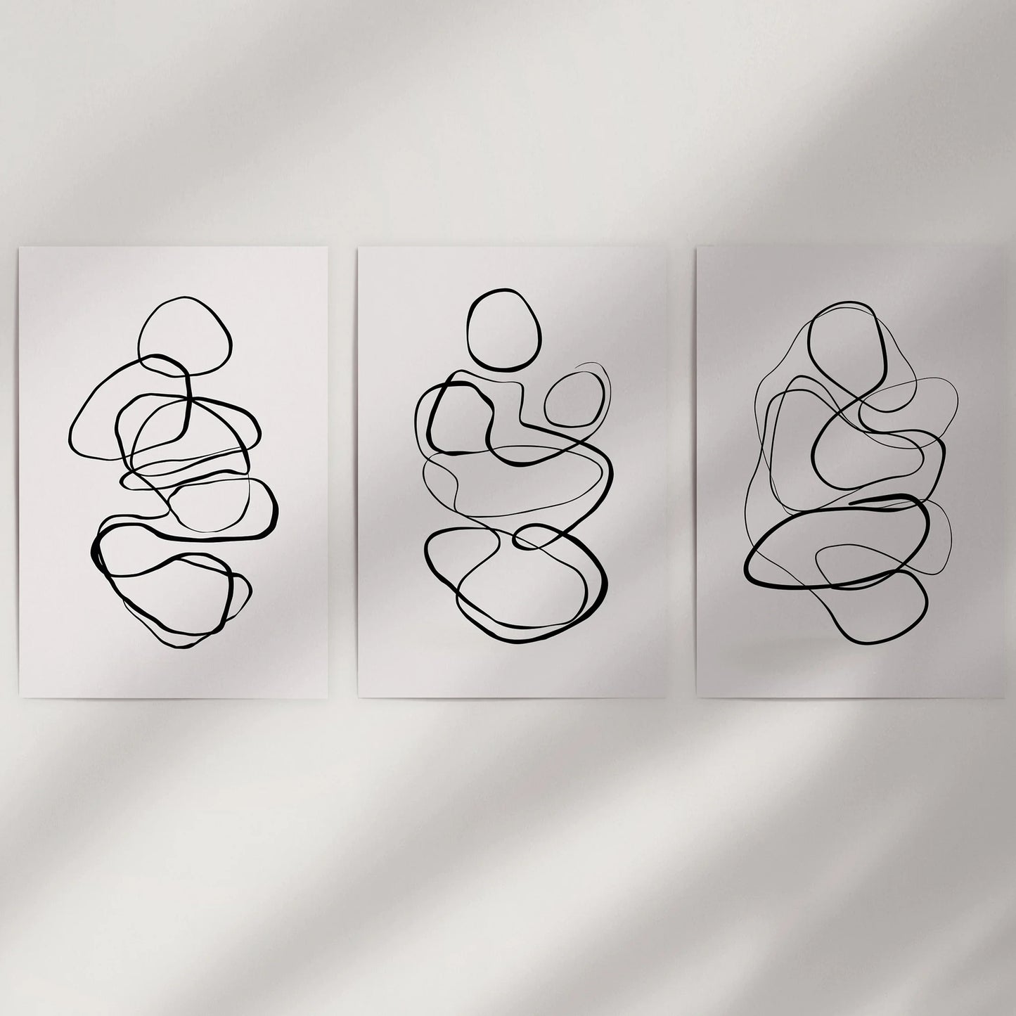 Minimalist contour art in a three-part poster set fills blank wall space; unframed prints keep the look light and easy to mix.