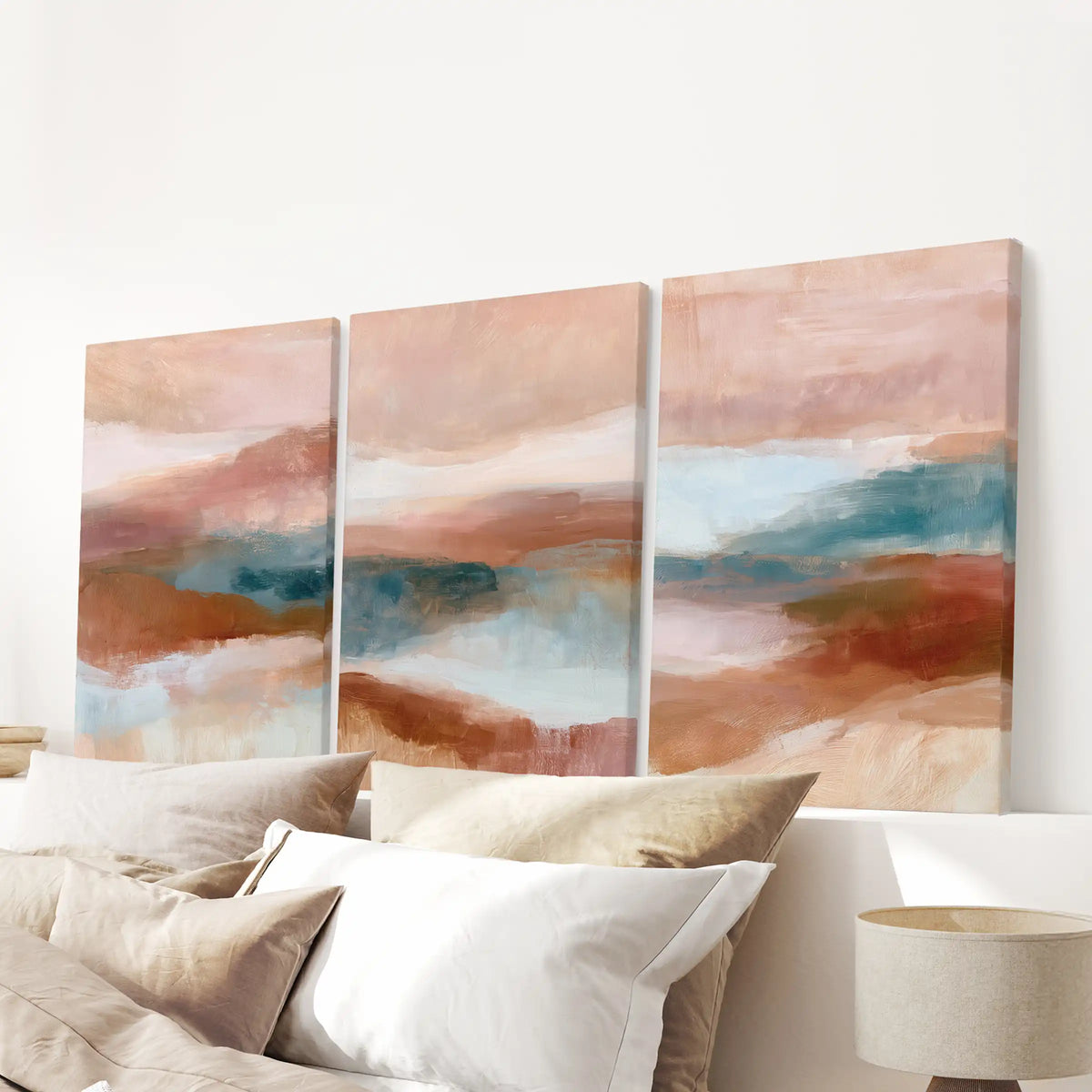 A set of three canvas wall prints with organic abstract shapes hangs above the bed, grounding the bedroom in soft earth tones.