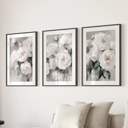 Abstract peony blossoms, a set of three wall prints in black matted frames, float over the living room sofa with soft, painterly petals and airy white space.