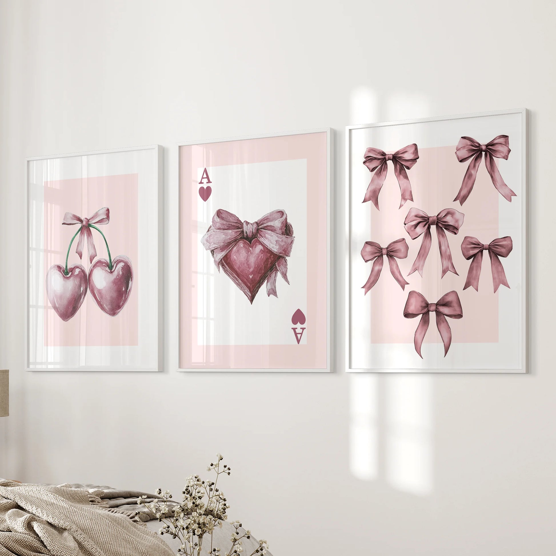 A three-piece wall art set of pink satin bows in white frames stacks by the bed, bringing gentle curves and a coquette charm to the bedroom.