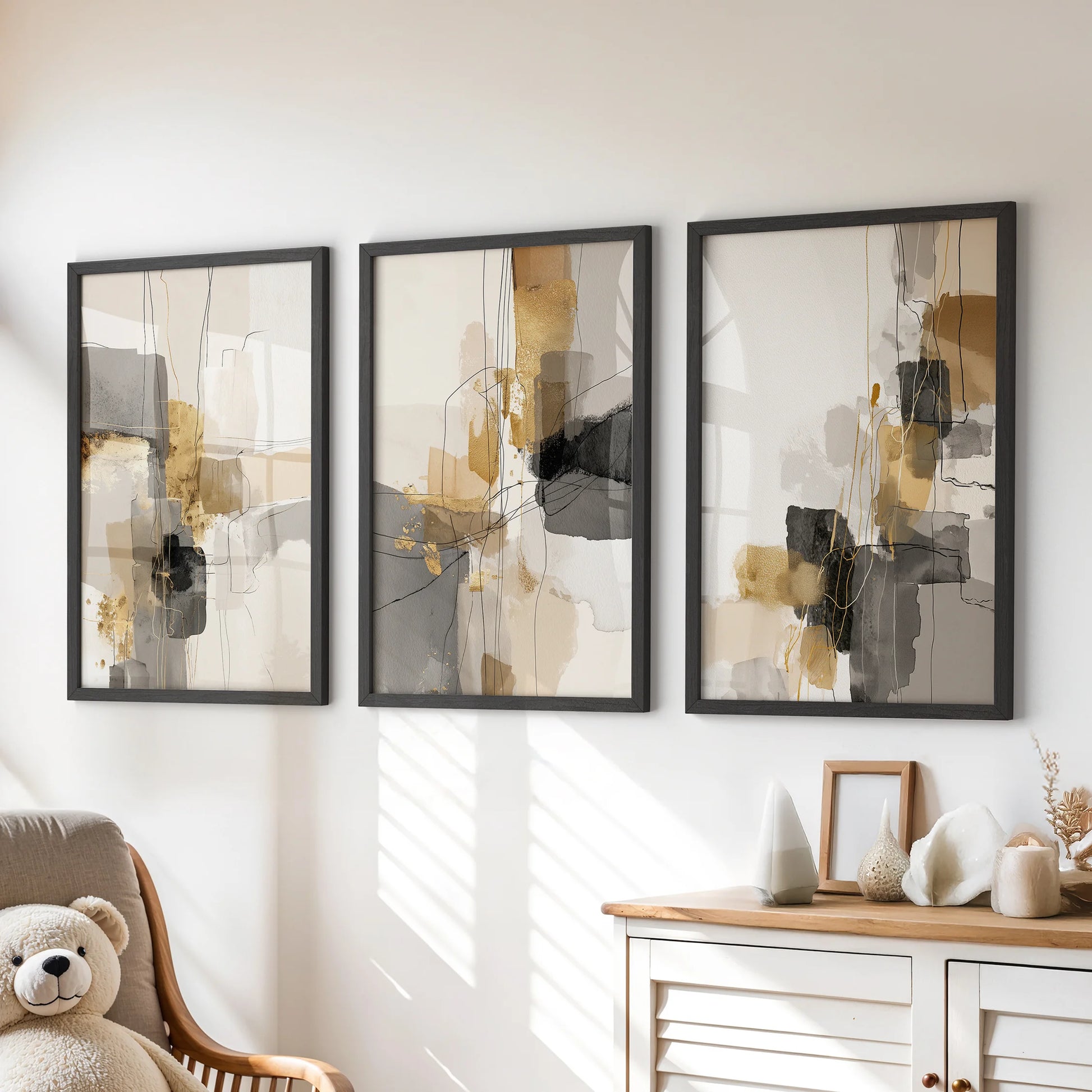 Three acrylic-texture wall panels in matte-black frames fill the kids playroom above the chest of drawers with bold but quiet shapes.