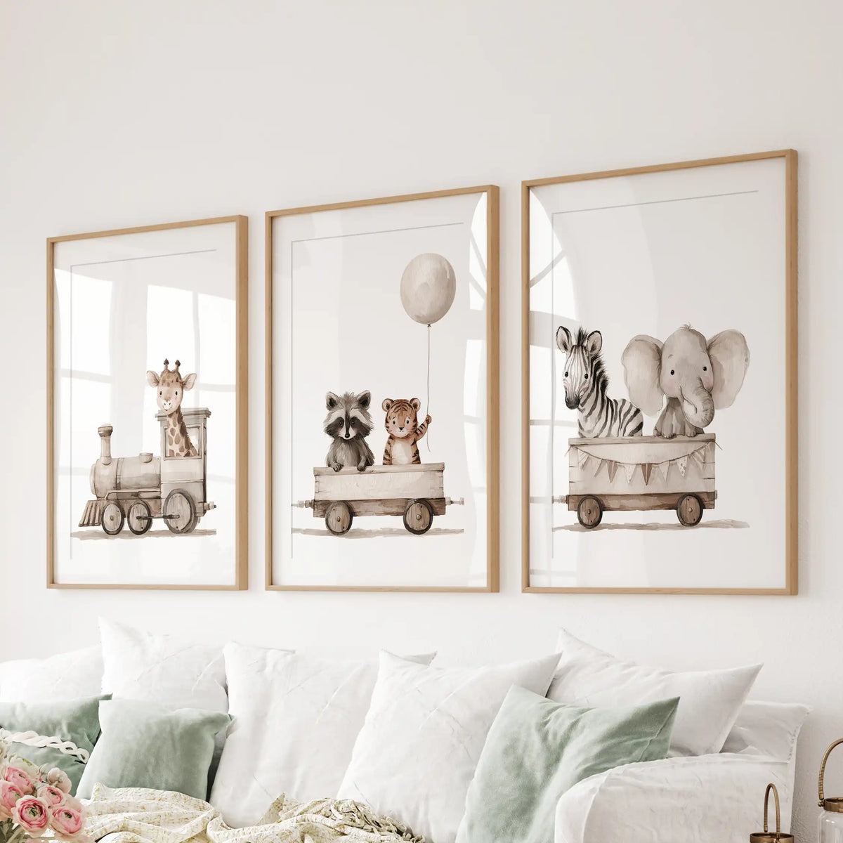 A set of three animal train prints in oak frames with white mats above a sofa.