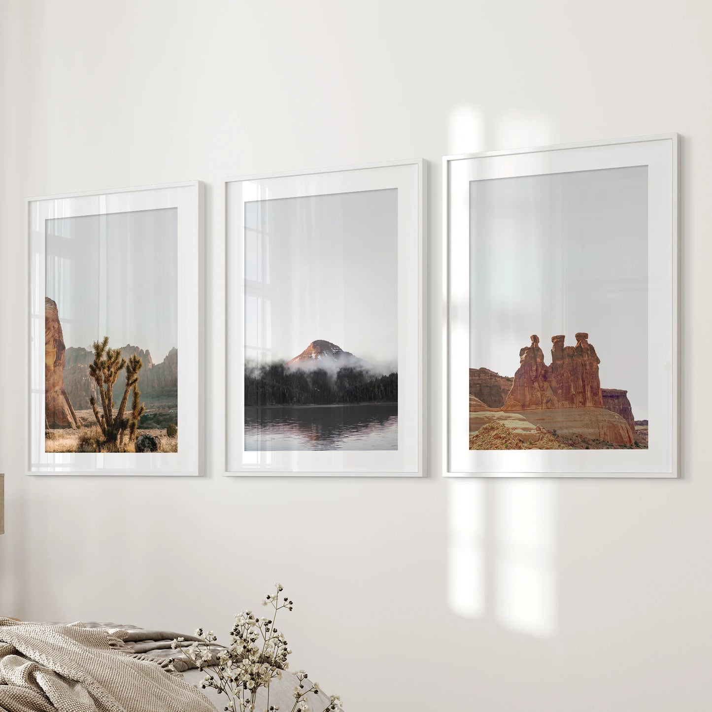 Red rock cliffs and mesas wall art triptych in white mat frames lines the wall beside the bed, lending a quiet, natural palette.