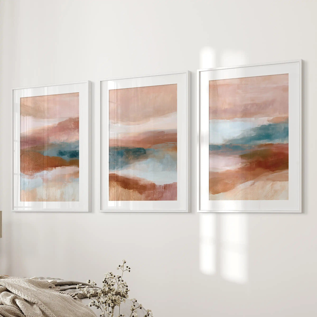 Earth-tone abstract triptych, a three-piece wall art collection in white frames with mats, brings quiet balance to the bedroom near the bed wall.