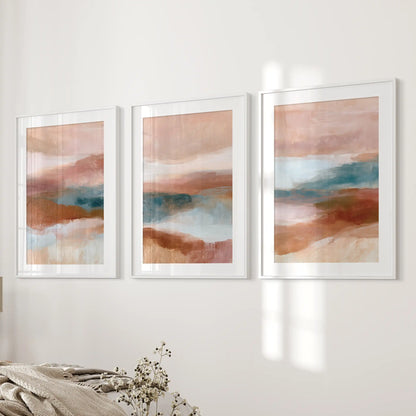 Earth-tone abstract triptych, a three-piece wall art collection in white frames with mats, brings quiet balance to the bedroom near the bed wall.