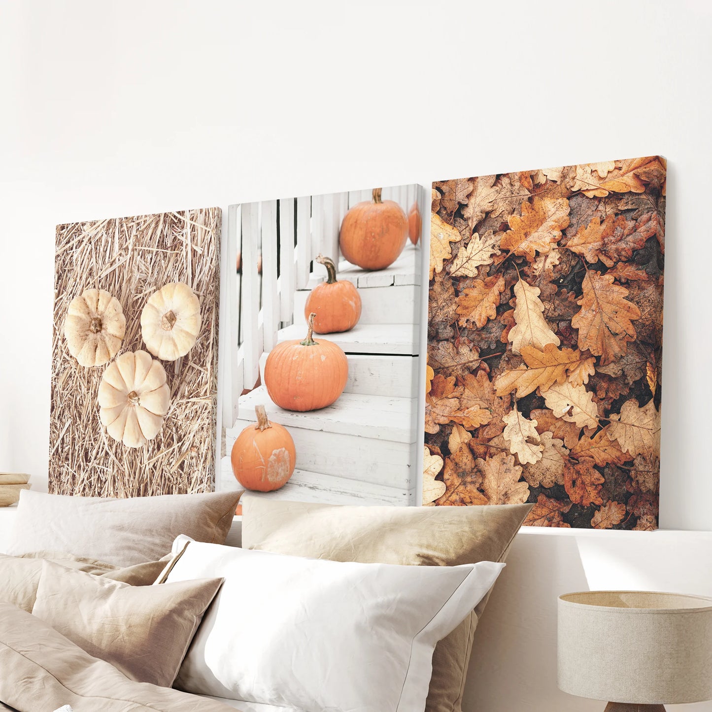 Stretched canvas triptych of farmhouse pumpkins hangs above the bed, casting warm, rustic autumn tones across the bedroom wall.
