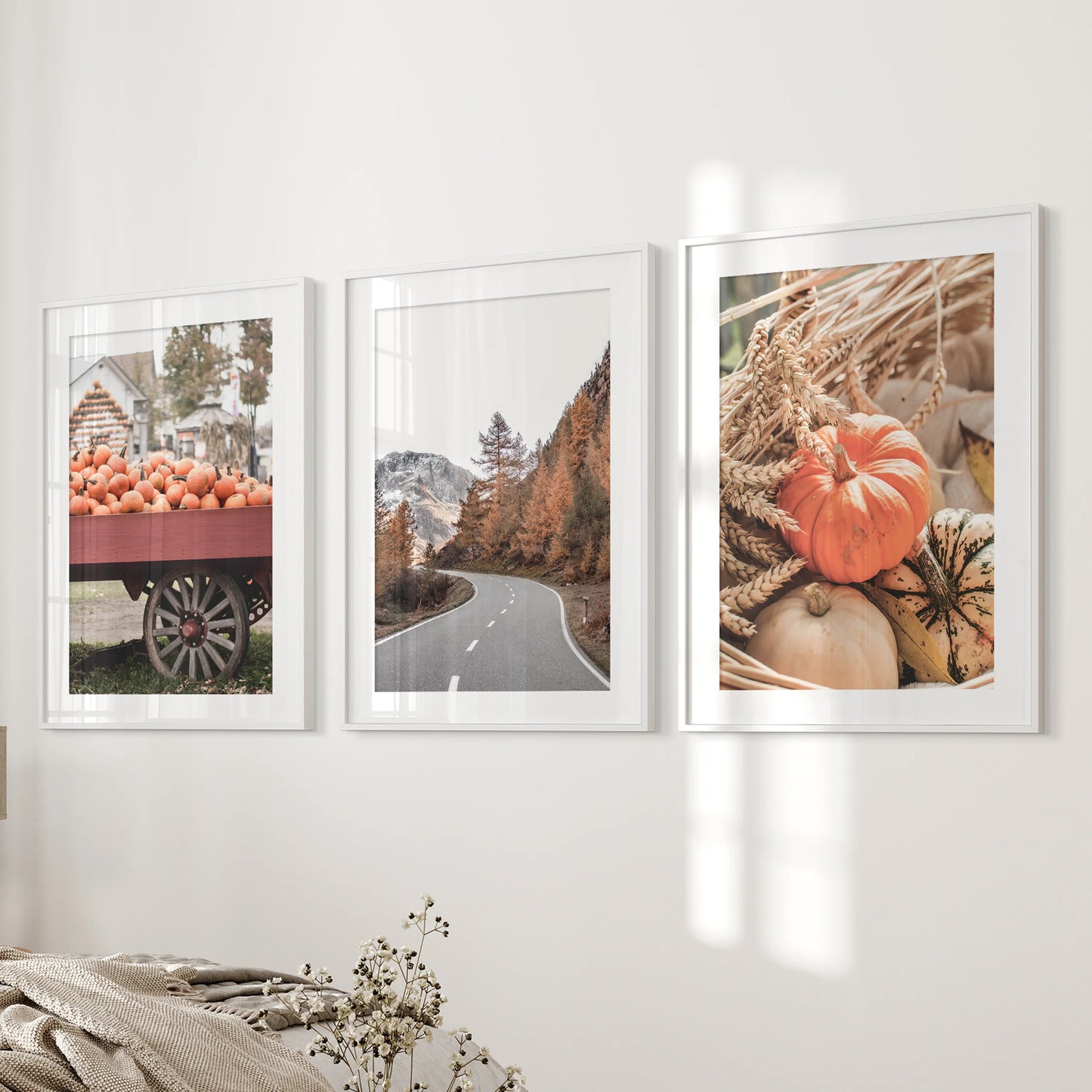 Set of three autumn tree prints in white frames with mats brightens a bedroom wall, layering russet tones and soft light for a calm feel.