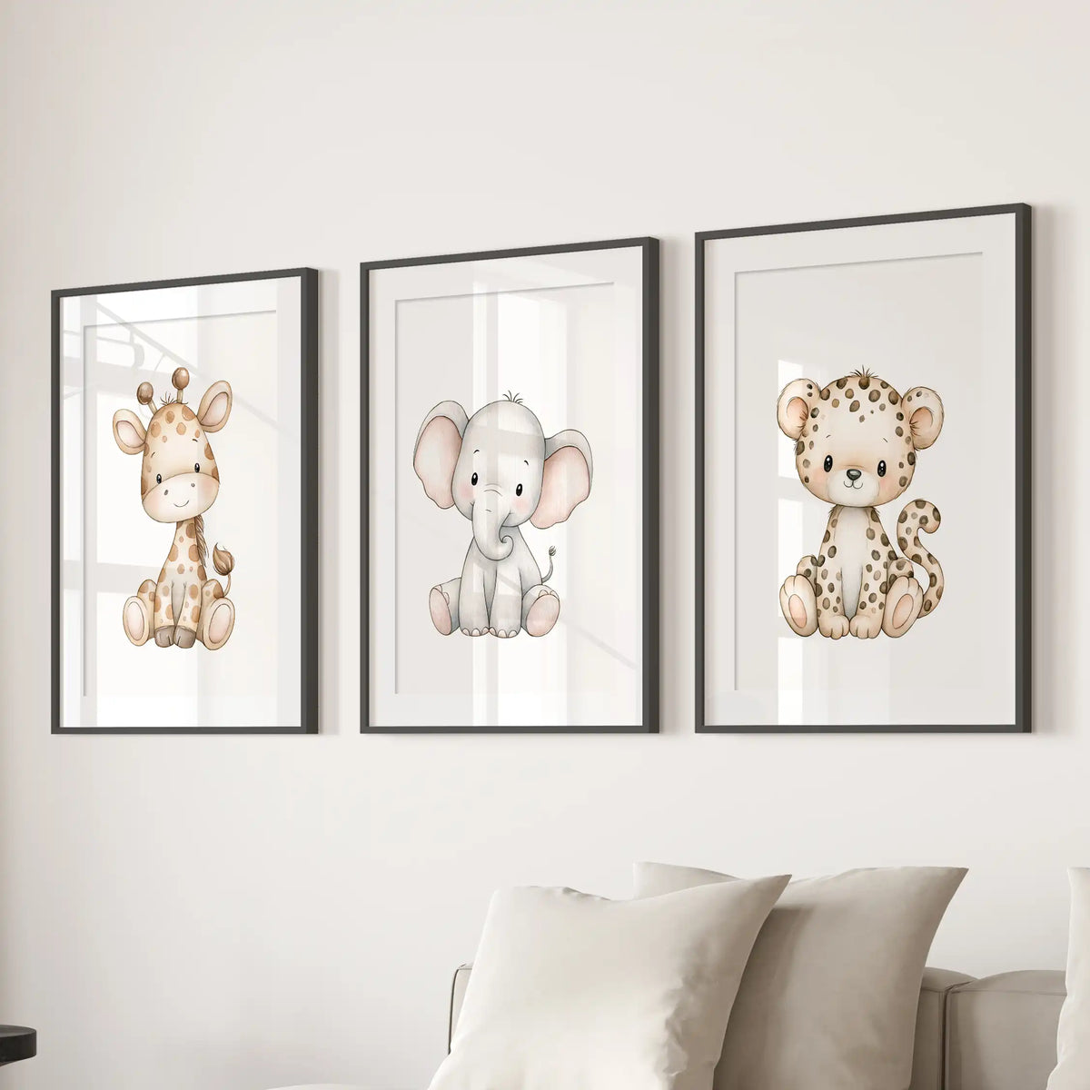 Baby animal prints in three matted black frames show a giraffe, elephant and leopard above a sofa.