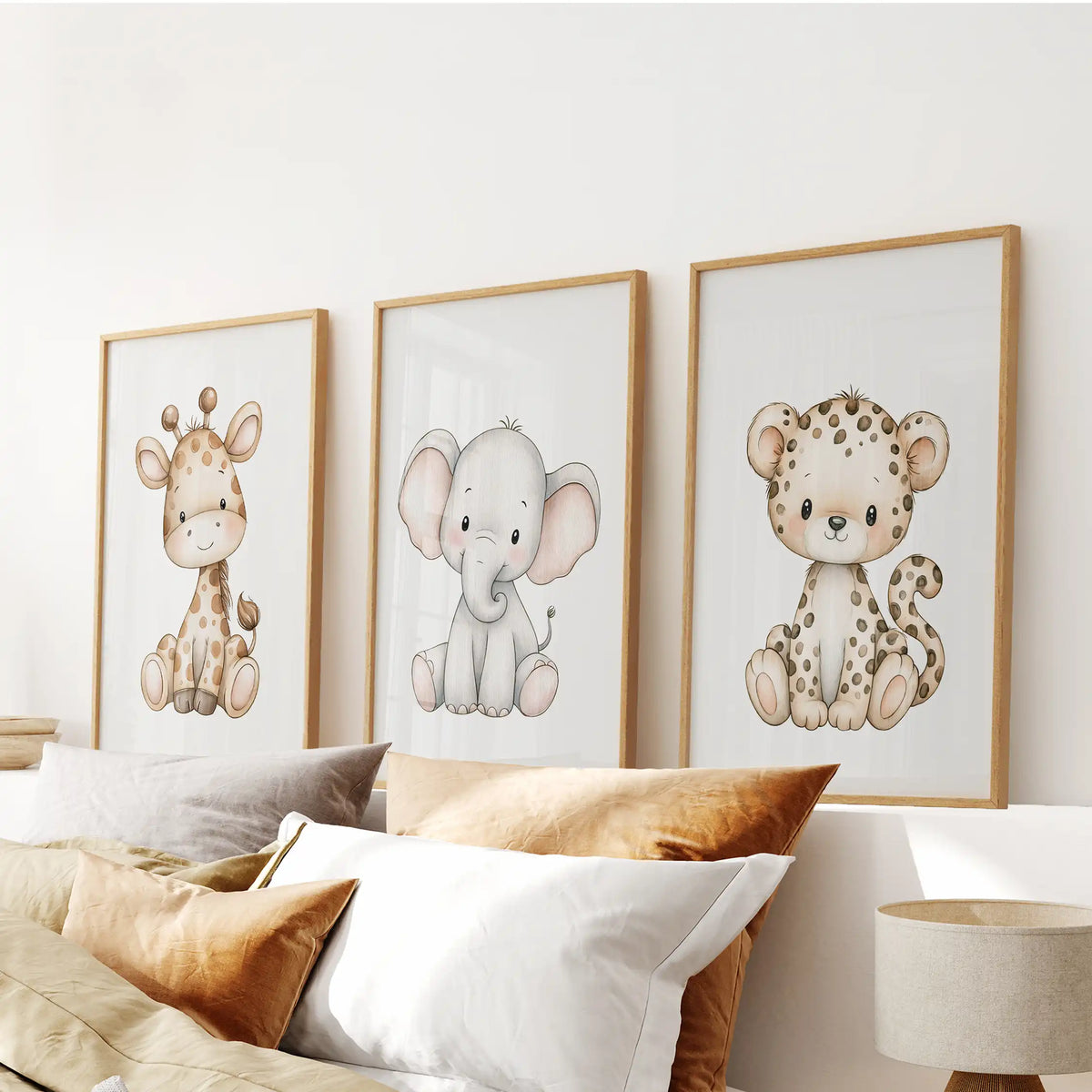 Above a bed, three oak-framed prints show a baby giraffe, elephant and leopard.