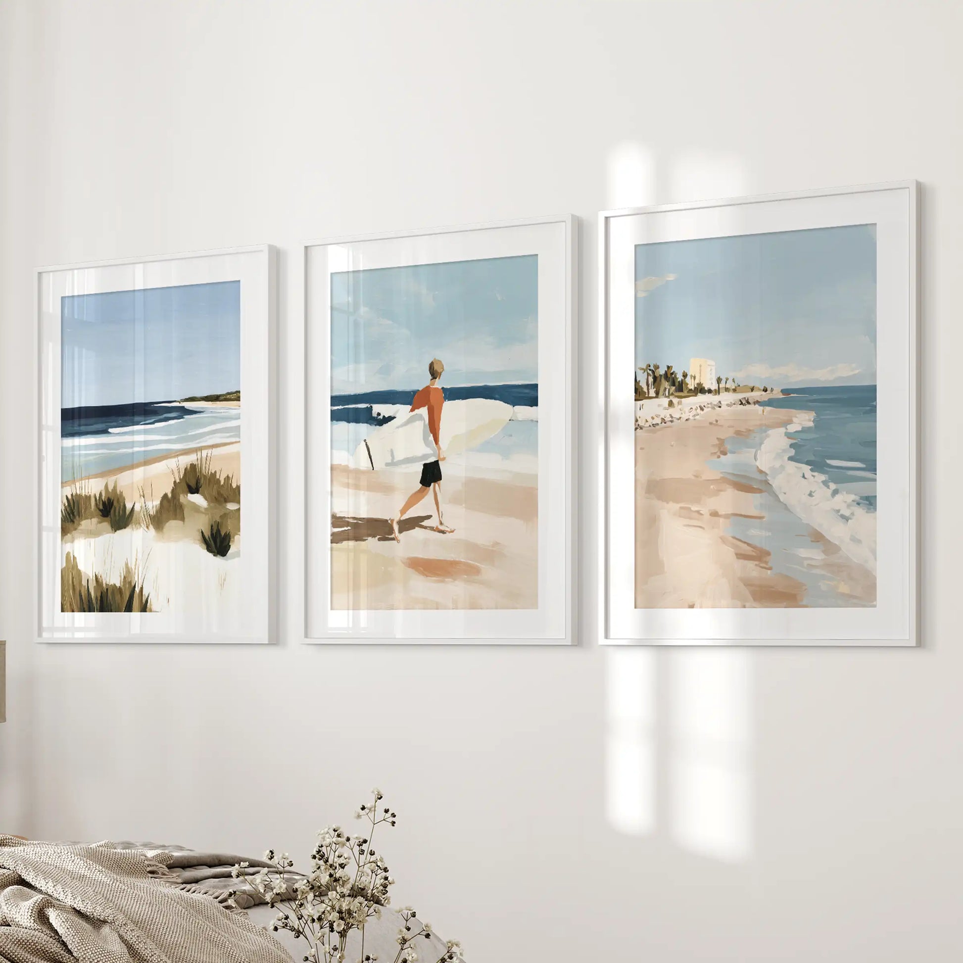 A trio of white-matted surfer prints refreshes the bedside wall, giving the bedroom soft coastal color and breezy movement.