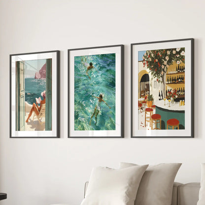 A trio of seaside café wall prints hangs behind the couch, each in a black-matted frame for a relaxed Mediterranean gallery feel.