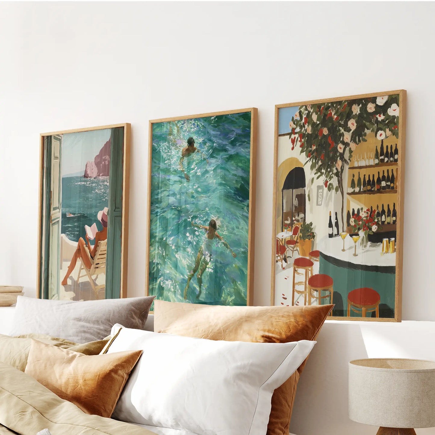 Amalfi Coast wall art set of 3 with swimming, sea view and Italian café prints in light oak frames above a bed