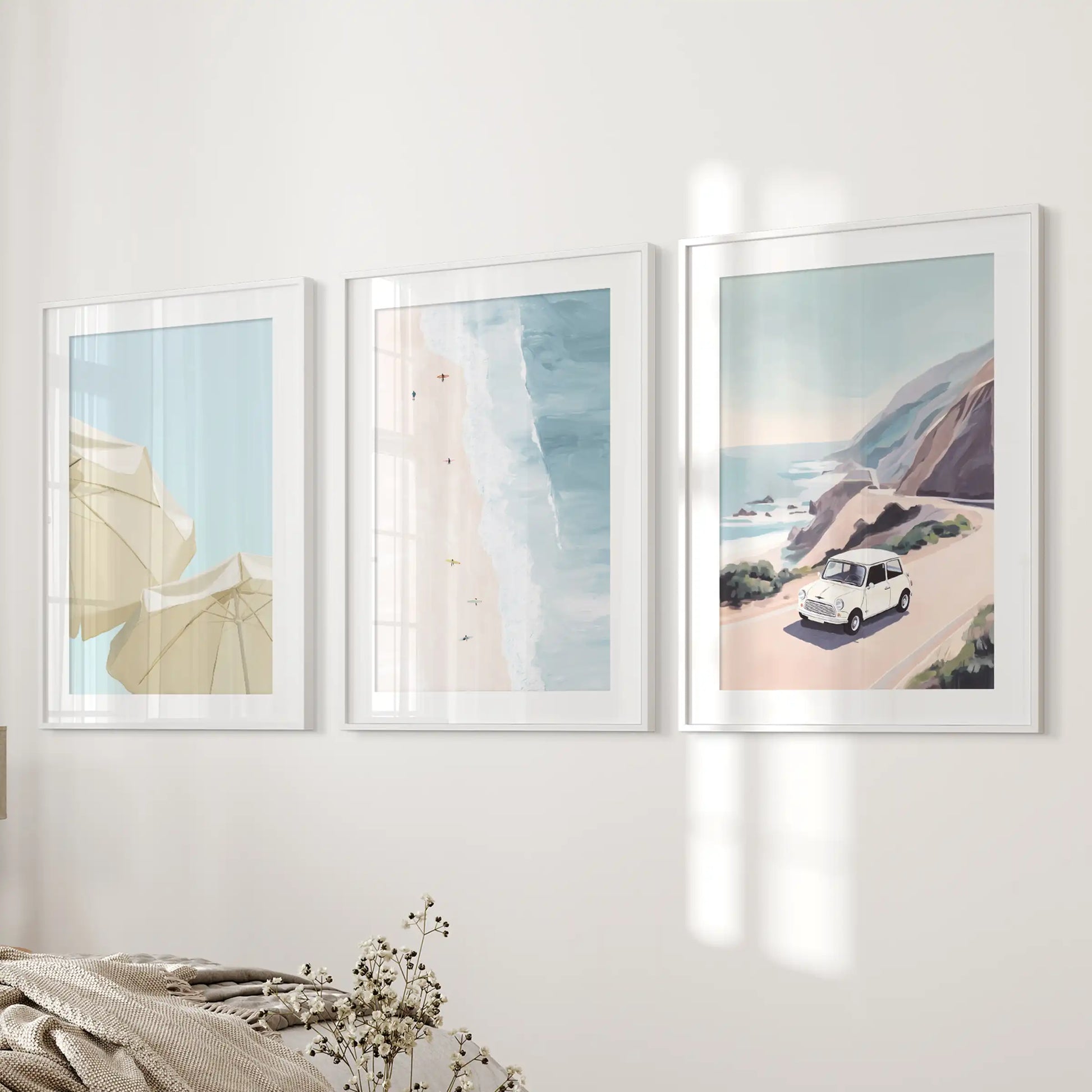 Ocean shoreline gallery wall, a 3-piece suite of white-matted, white-framed prints, layers calm beside the bedroom wall next to the bed.