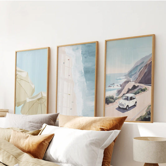 Pastel seaside landscape wall art, three pictures in oak frames, floats serenely above the bedroom bed, adding soft color to a calm retreat.