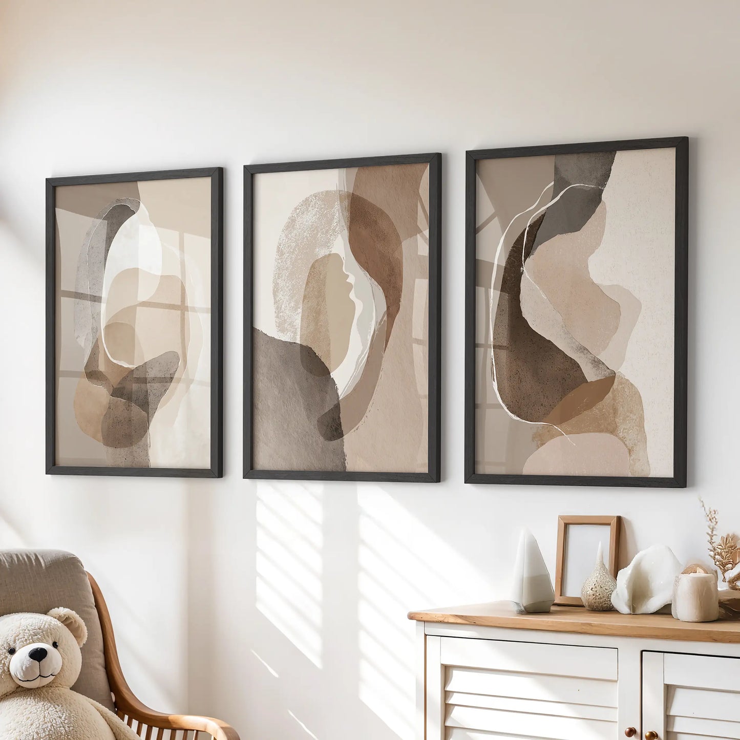 Neutral abstract wall art three-print set, black framed, rests over the chest of drawers to add soft earth tones to a children’s room.