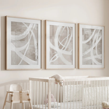 Gallery set of three contemporary compositions matted in natural oak frames hangs over the cot, soothing the infant room’s space.