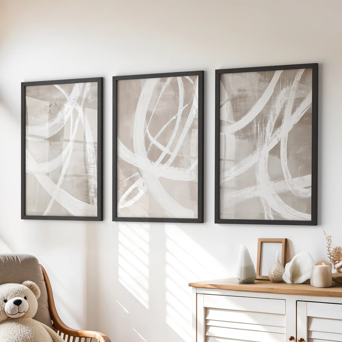 Beige color palette abstract prints, a three-piece set, sit in black frames above the chest of drawers in the children’s room.