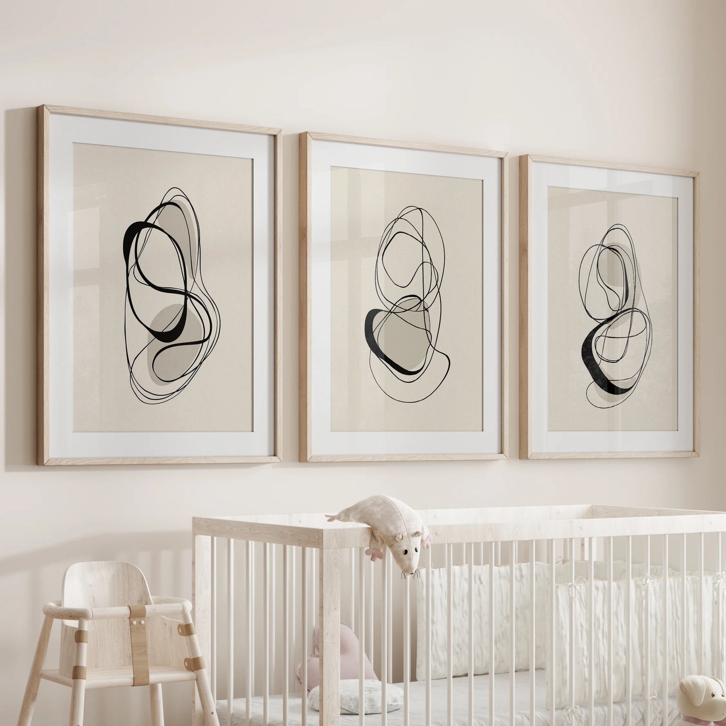 Three-piece wall art set of soft contour sketches in natural wood frames, resting above an infant’s cot for a warm, neutral accent.