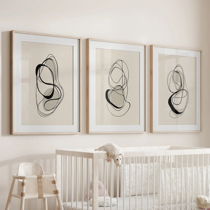 Three-piece wall art set of soft contour sketches in natural wood frames, resting above an infant’s cot for a warm, neutral accent.