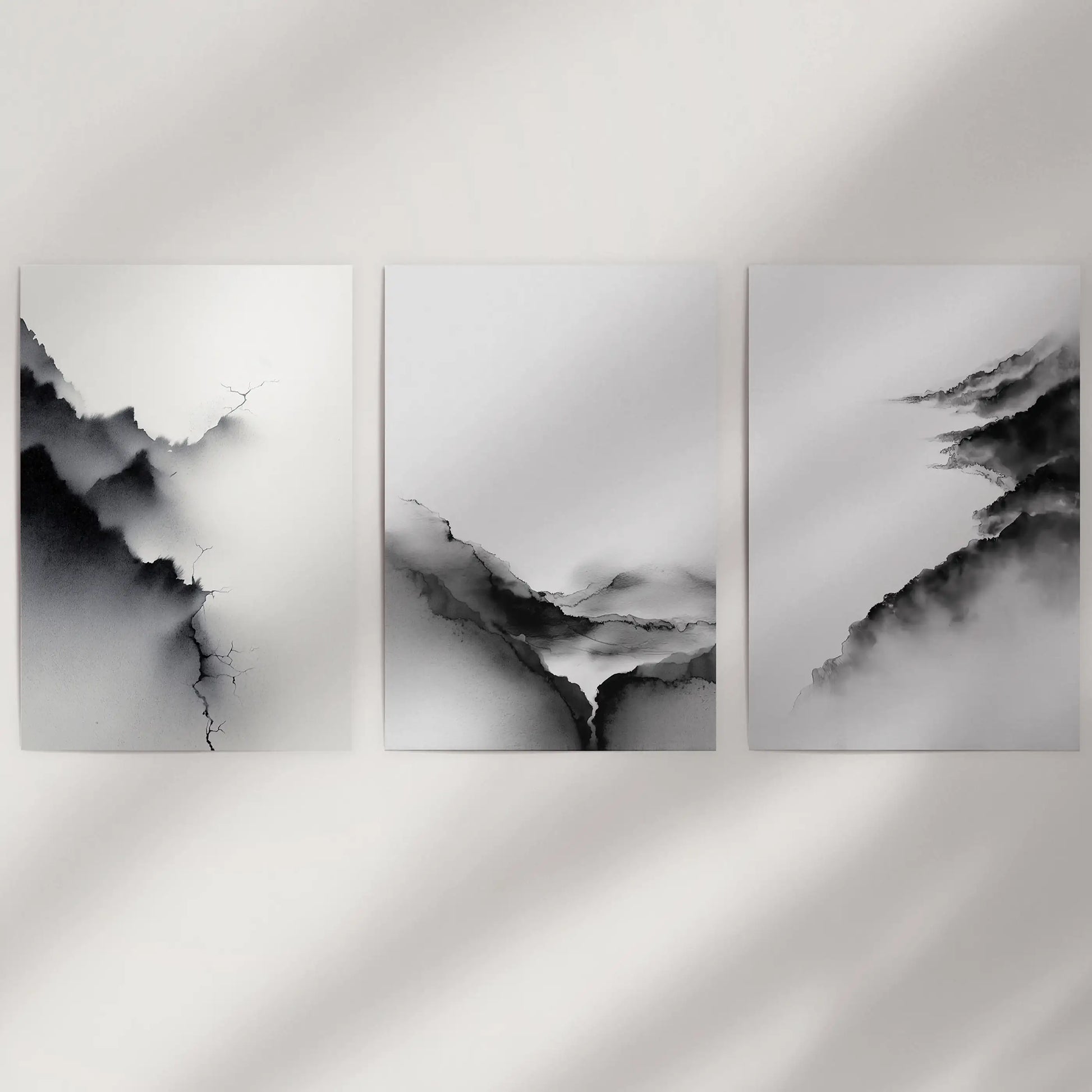 Three unframed poster prints feature monochrome abstract landscapes, bringing a crisp graphic calm to a plain wall.