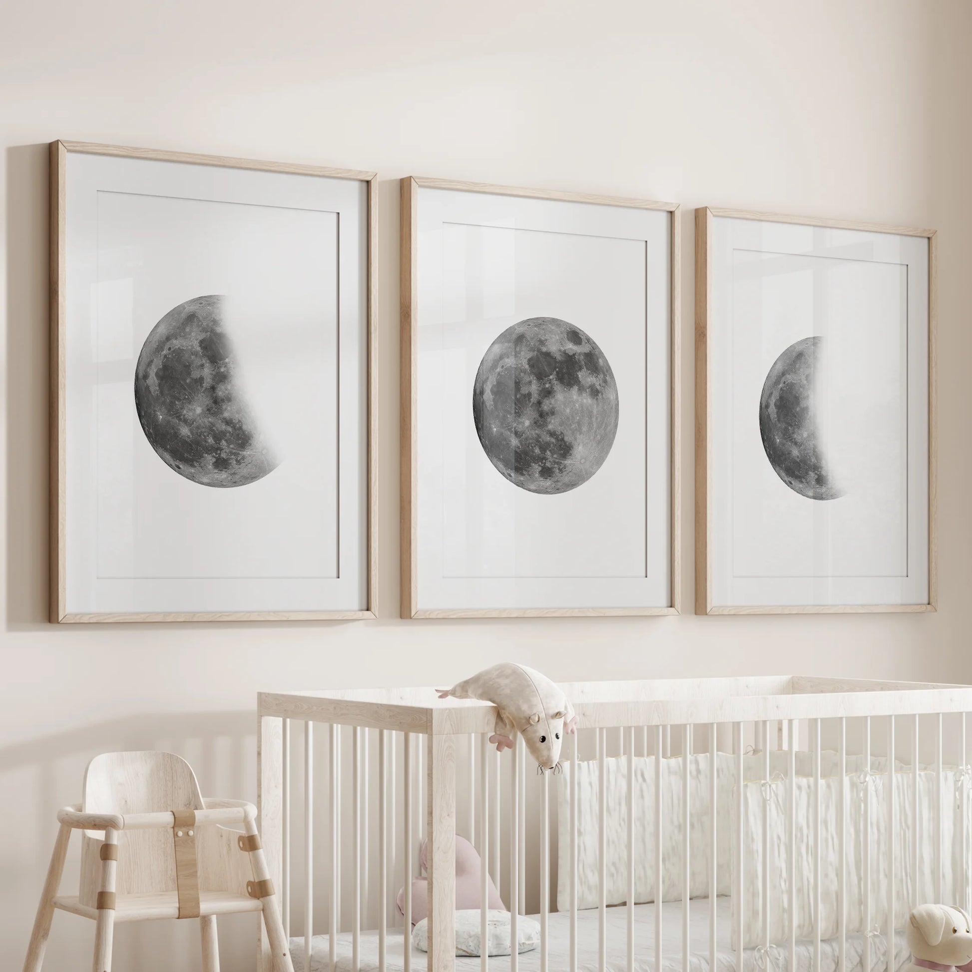 Black and white moon photography set of three wall art prints in matted wooden frames hovers over the bassinet, soothing the nursery with quiet lunar tones.
