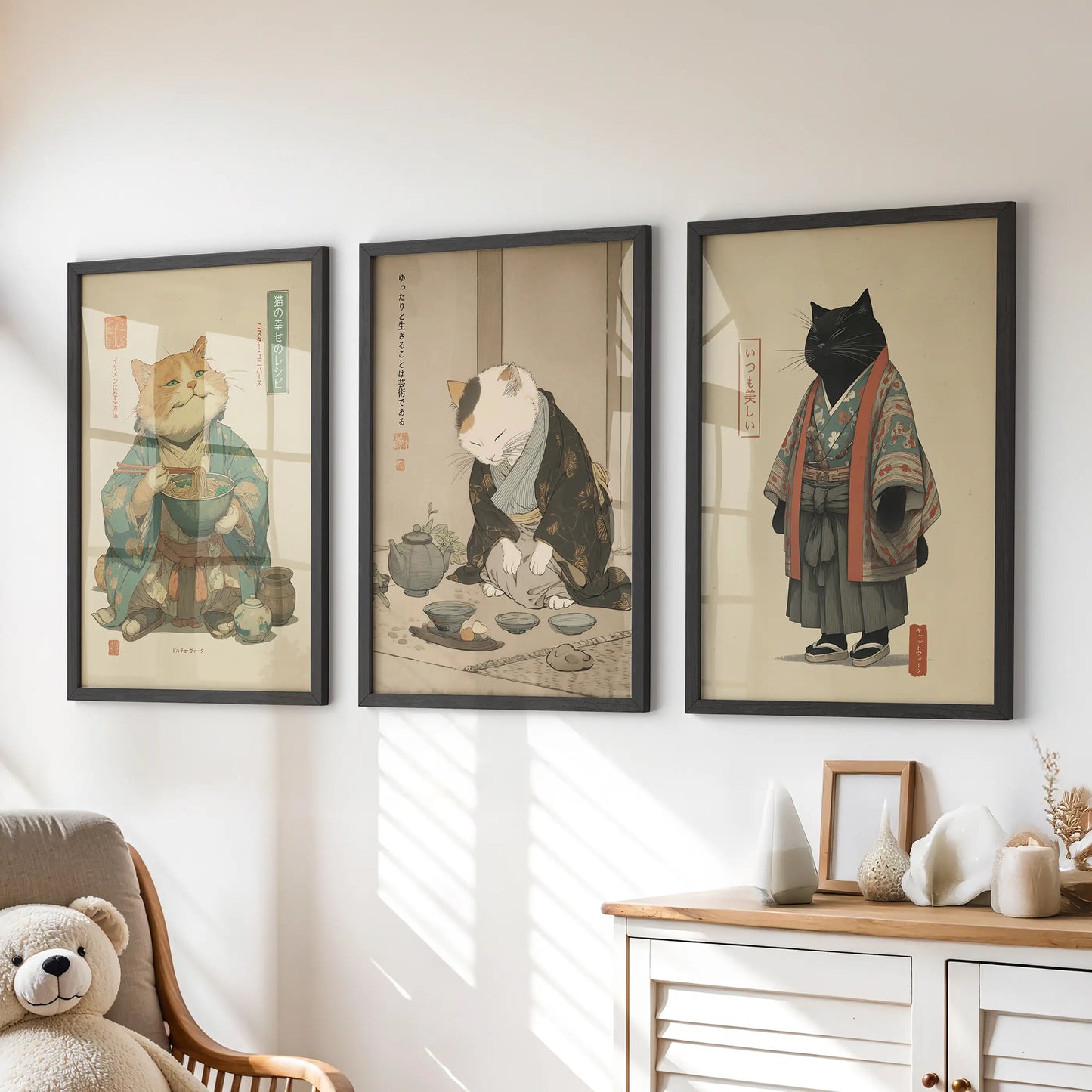 A playful trio of black-framed cat artworks featuring a ramen bowl hangs above the children's drawers, bright with storybook charm.