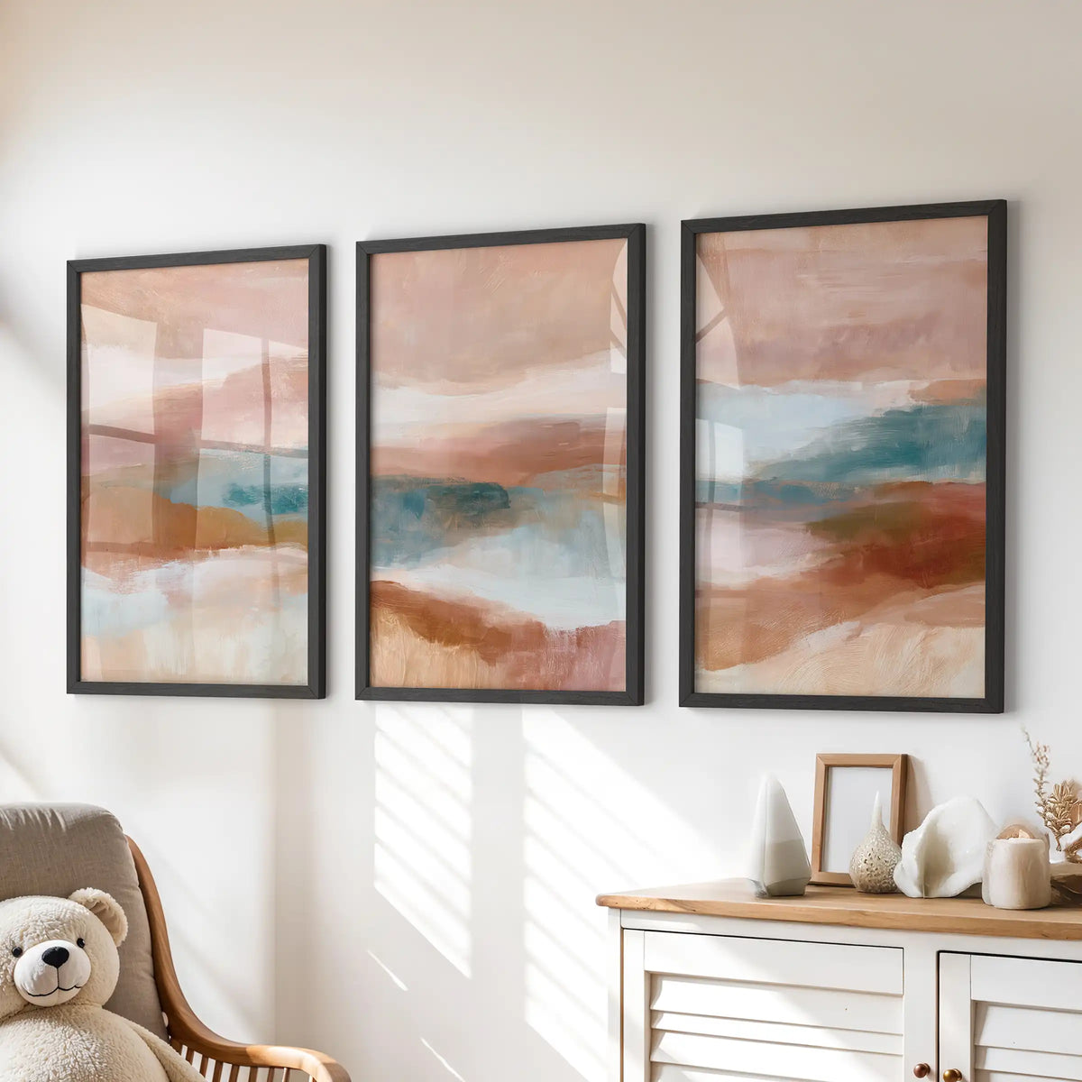 Blush pink, terracotta and blue color fields, a three-piece wall art set in slim black frames, brighten the kids playroom above the dresser.