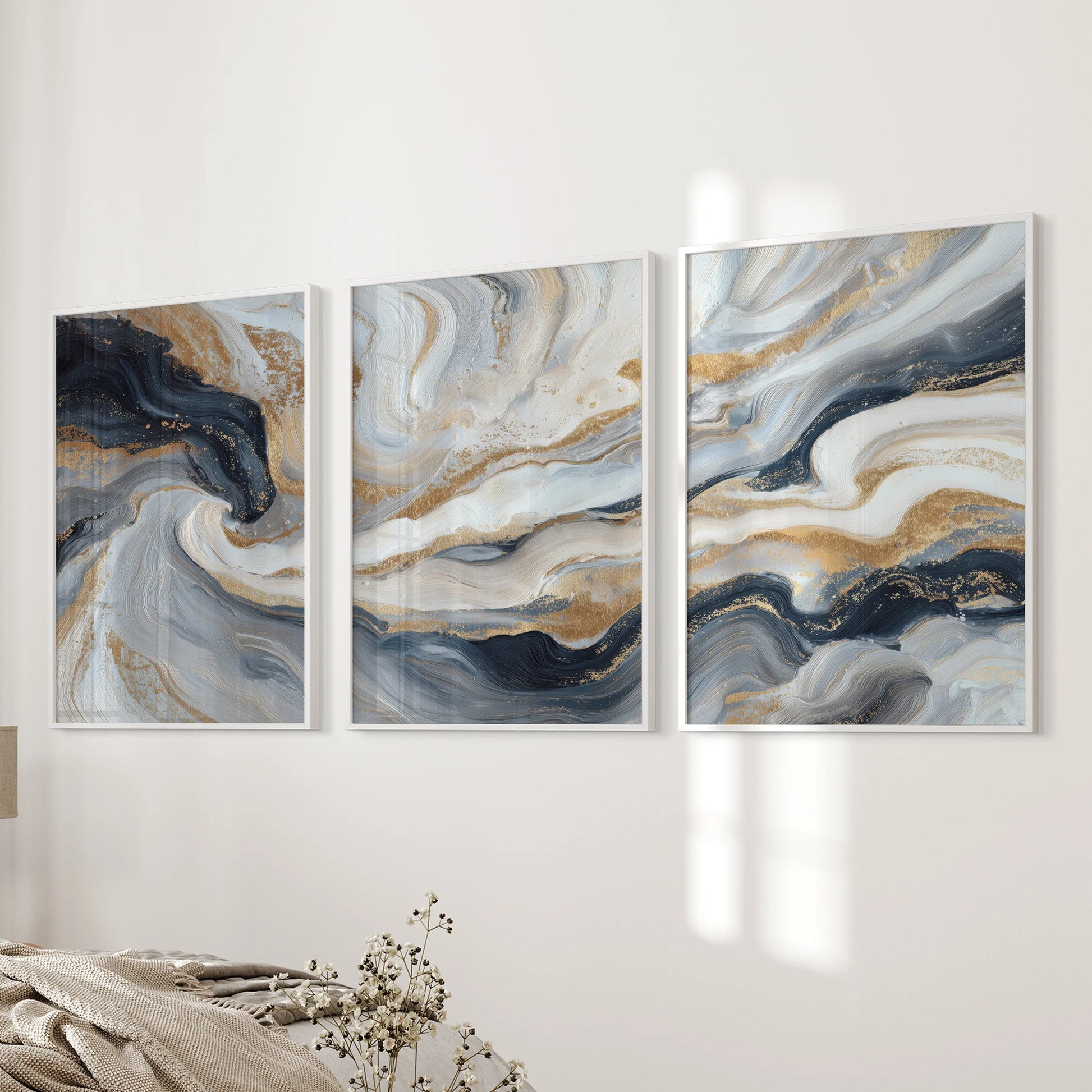 Three minimalist blue and gold abstract prints in white frames rest quietly on the bedroom wall near the bedside.