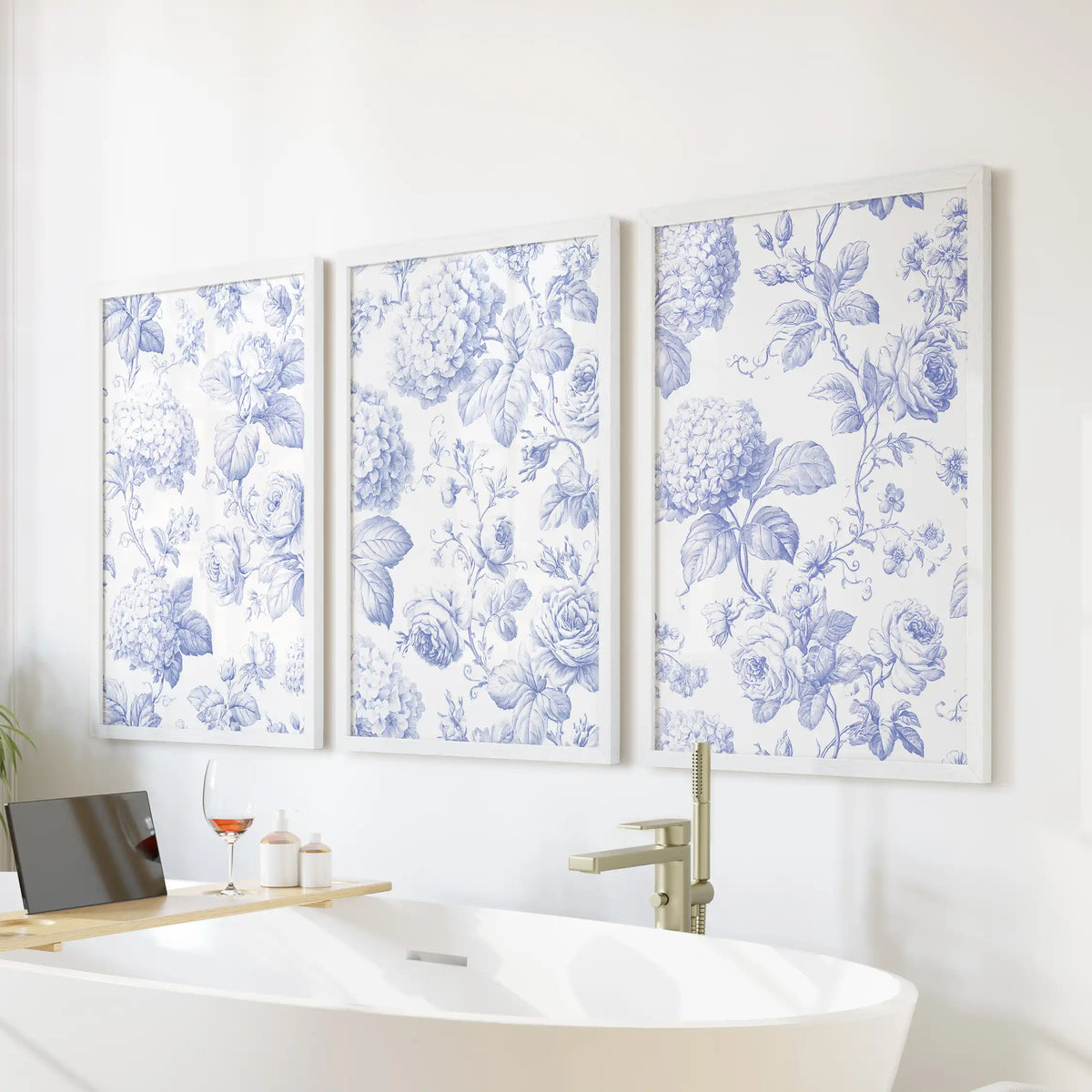 Above a freestanding bathtub, three blue botanical pattern prints hang in white frames.