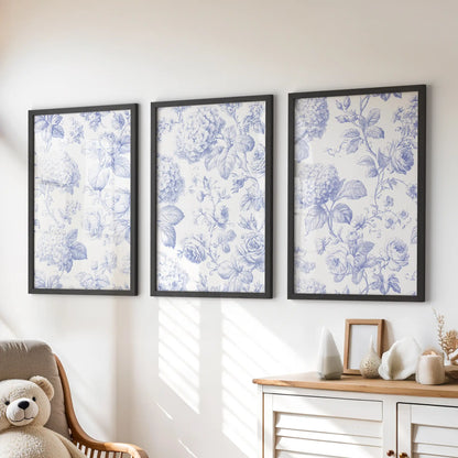 Fine blue roses and hydrangea clusters fill three black-framed prints above a dresser, beside a chair with a teddy bear.