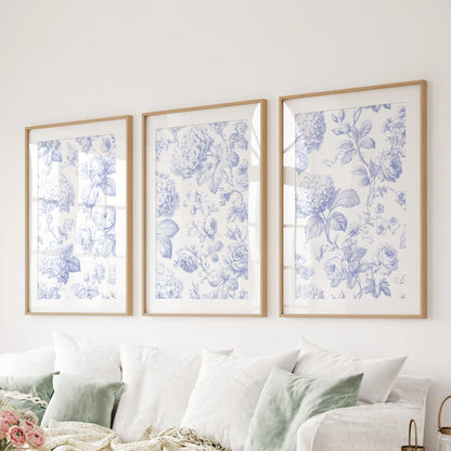 Above a sofa, three oak frames with white mats display detailed blue flower patterns on cream backgrounds.