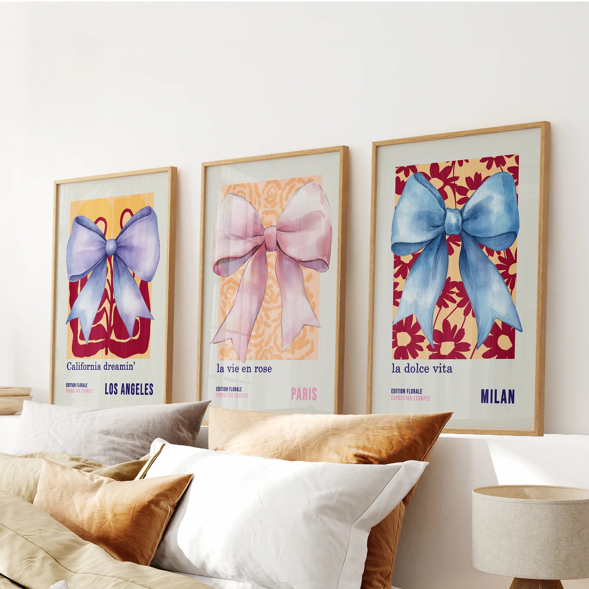 Three thin wood-framed art prints of 70s-style bows stretch above the bed, softly uniting blue and pink hues across the bedroom.